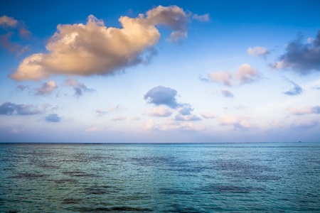 sunrise over the turqoise ocean with blue sky and some cloudsの写真素材