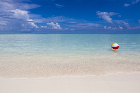 plastic beach ball swimming in the sea with a blue skyの写真素材