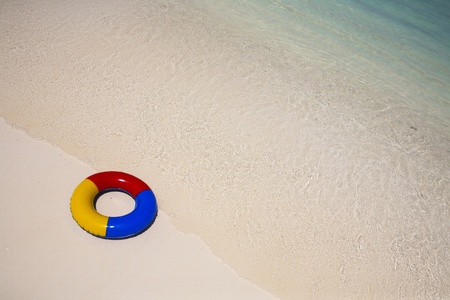 beach with a red, yellow and blue plastic swimming ring in the sandの写真素材