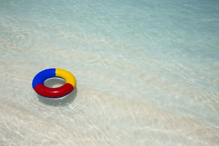  red, yellow and blue plastic swimming ring floating in a turquoise sea