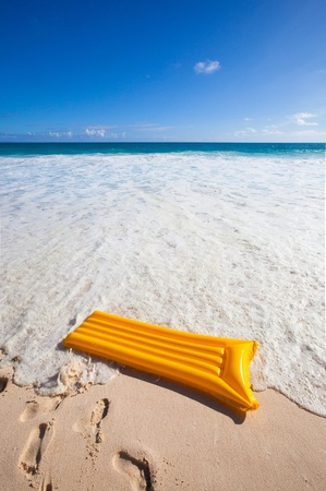 yellow air mattress at the beach with a turquoise sea and blue skyの写真素材
