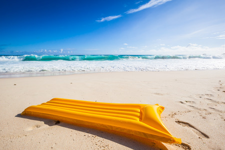 yellow air mattress in the sand of a tropical beach with a turquoise sea and blue sky in the...
