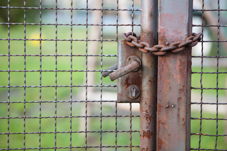rusty door in an iron fence locked with a chain の写真素材