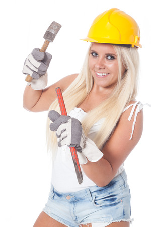 sexy young blonde girl working as building labor with a yellow helmet, hammer and chisel or gougeの写真素材