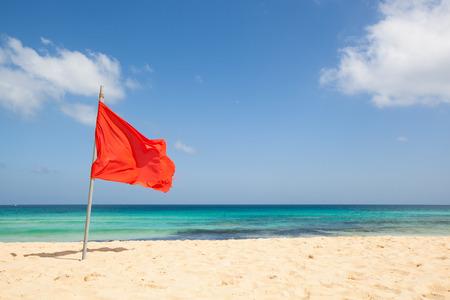warning sign of a red flag at a beautiful beach with a blue sky and a turquoise sea, Fuerteventura, Canary Islands, Spain, Europeの写真素材