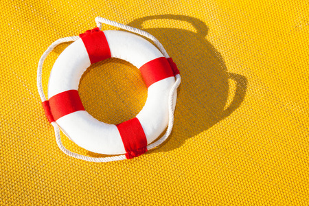 red and white colored life belt in front of a yellow backgroundの写真素材