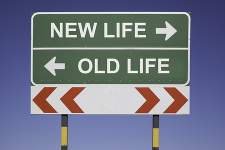 green traffic sign in front of a blue sky, horizontal arrows showing two directions and a red white road warning post  Business concept for activity and decision  New life or old lifeの写真素材