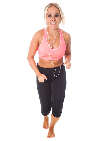 young blond girl in pink and black sportswear jogging with music player in front of a white backgroundの写真素材