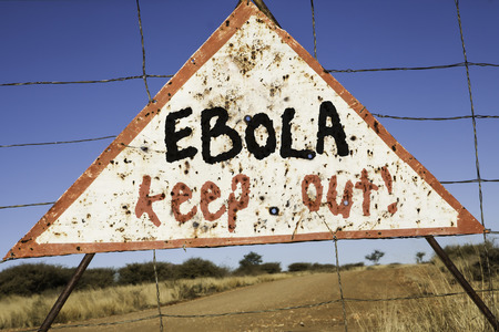 old rusty warning triangle at a fence in Africa  with the words Ebola keep outの写真素材