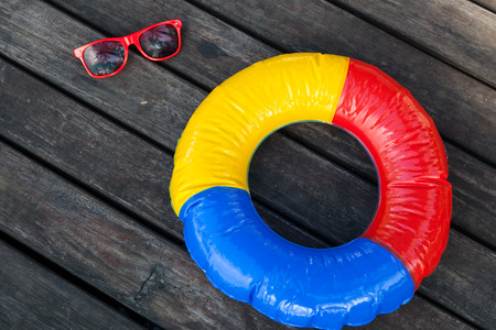 colorful swimming ring and red sunglasses on the wooden planks of a jetty