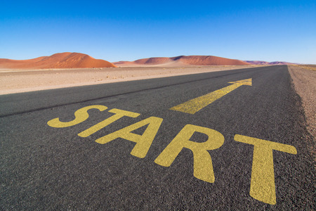 asphalt road in the desert with a yellow arrow and the word START leading to the horizon. Business concept for motivation and successの写真素材