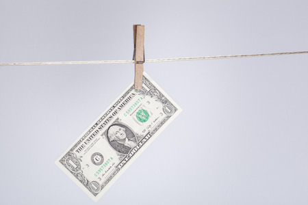 clothespin fixing a one dollar banknote on a clothesline. financial concept and background for money...
