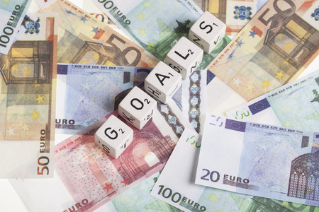 Euro banknotes with letter cubes and the word goals. finance concept for making more profit or raise incomeの写真素材