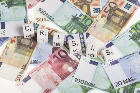 Euro banknotes with letter cubes and the word crisis. finance concept for euro currency crisisの写真素材