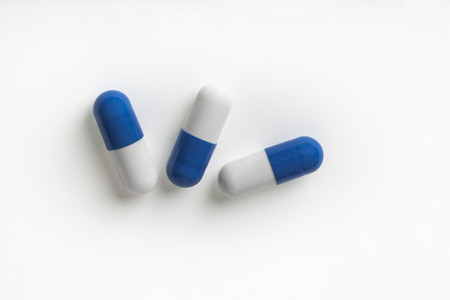 three blue and white pills on a white background. health concept for medicine and drugsの写真素材