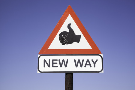 red and white warning triangle traffic sign with a human hand showing thumb up and the words new way, business concept for motivation and successの写真素材