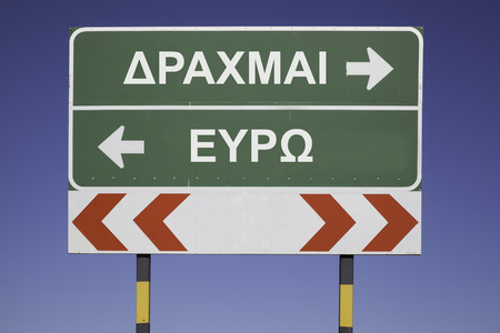 Green traffic sign with arrows, showing the decision between the way to Euro or the greek currency Drachma. Financial concept for the greek debt crisis and the word Drachma and Euro in greek lettersの写真素材