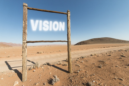 empty wooden frame of a sign in the desert and the word vision written in the sky. Business concept for success and motivationの写真素材