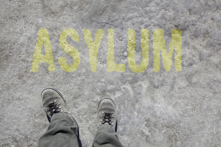 legs with gray boots and the word Asylum on the ground. Concept for Refugees on their way to Europe.の写真素材