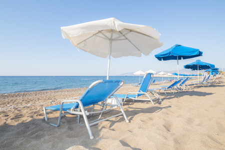blue and white sunshade and sunbeds at the shingly Latsi beach, Cyprus island, Greece, Europeの写真素材