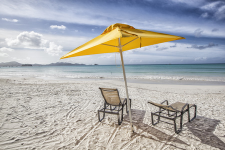two sunbeds under a yellow sunshade at the beach, concept for summer, holidays travel and vacationの写真素材
