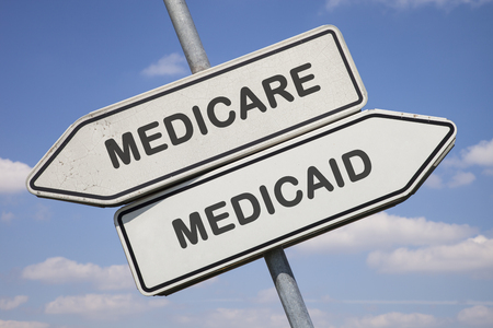 two white direction signs with arrows and the words medicare and medicaid, political and social concept for us health careの写真素材