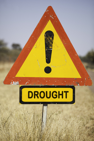 red warning triangle and the word drought in dry grassland, environmental concept for climate change, Botswana, Africaの写真素材