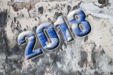 grey old and dirty wall and the word 2018 written in blue and white sky letters, concept for turn of...