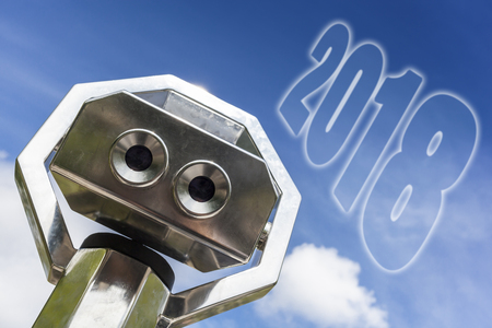 pair of binoculars and the word 2018 written in the blue sky, business concept for vision and turn of the yearの写真素材