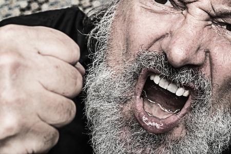 portrait of a aggressive crying man with a clenched fist, open mouth snd  grey full beard, concept for violence, hate and aggressionの写真素材