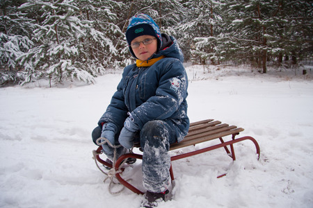 White cold winter a little boy sitting on a sleighの写真素材