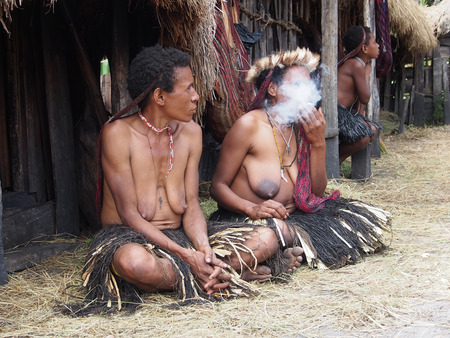 Wamena, Indonesia - January 23, 2015: Dani tribe Women with children in front of their hutsのeditorial素材