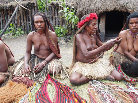 Wamena, Indonesia - January 23, 2015: Dani tribe Women with children in front of their hutsのeditorial素材
