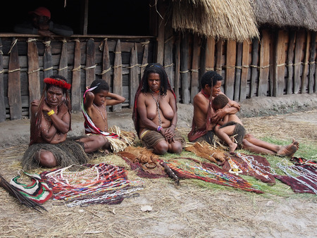 Wamena, Indonesia - January 23, 2015: Dani tribe Women with children in front of their hutsのeditorial素材