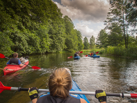 River Pilawa, Poland - August 25, 2015: The Group of kayaks flowing down the river between trees overturnedのeditorial素材