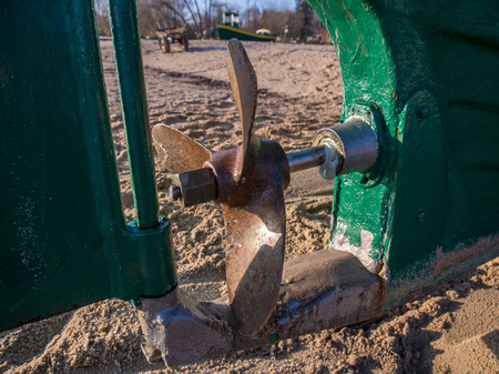 Steel propeller and rudder of a fishing boat on a sandy beachの写真素材