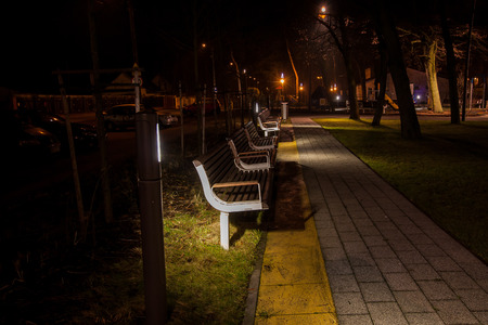 A night photo of benches in the park lit only street lampsのeditorial素材