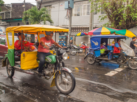 Iquitos, Peru- May 14, 2016: Various rickshaws on a  street of a small town.のeditorial素材