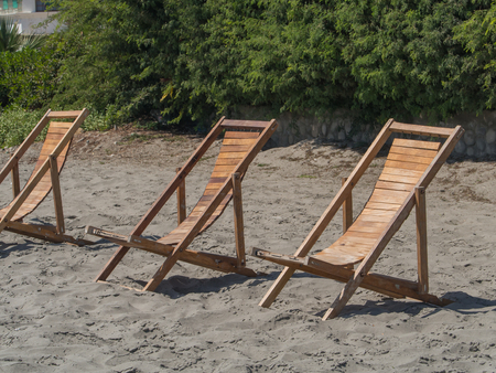 Three wooeden sunbeds on the shore of ocean in Paracasの写真素材