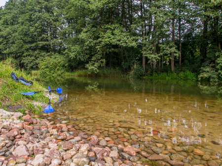 Paddles and  life jackets on a  bank of a river Wdaの写真素材