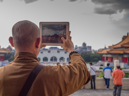 Taipei, Taiwan - October 02, 2016: Buddhist monk takes a picture with his iPad on the  Liberty Square in Taipeiのeditorial素材