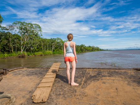 Amazon River, Peru - May 12, 2016: Young woman looking for  the Amazon River from the deck of cargo boatのeditorial素材