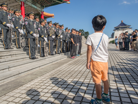 Taipei, Taiwan - October 02, 2016: Child is looking for Taiwanese soldiers orchestra wearing various style, ceremonial uniforms.  In the background National Concert Hall and Chiang Kai-shek Memorial Hall on Liberdade square in Taiwanのeditorial素材