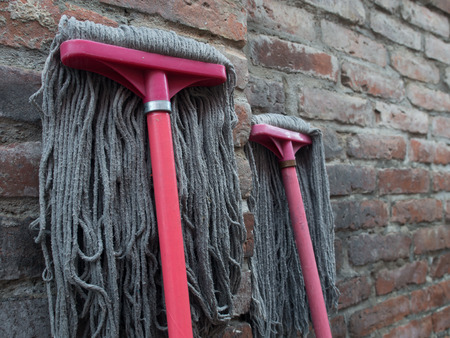 Floor cleaning brushes leaning against a brick wallの写真素材