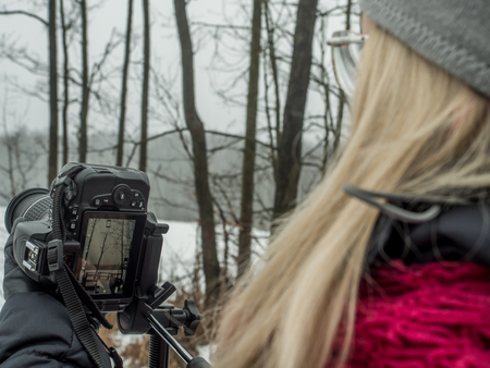 Woman taking winter photos and  looking at camera displayの写真素材