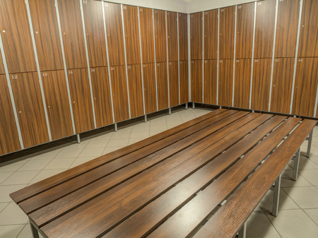 The row of wooden cabinets and a wooden bench in a fitness club dressing roomの写真素材