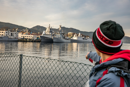 Bergen, Norway - February 11, 2017: Boy pointing at  naval vessels in  the Port of Bergenのeditorial素材