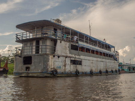 Santa Rosa, Peru - December 11, 2017: Cargo boat on the Amazon river on the background of the sun setのeditorial素材