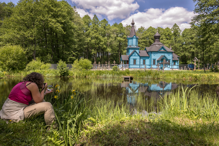 A woman takes picture of  blue, wooden orthodox church.  Podlasie. Podlachia. Poland, Europe. The region is called Podlasko or Podlaszeの写真素材
