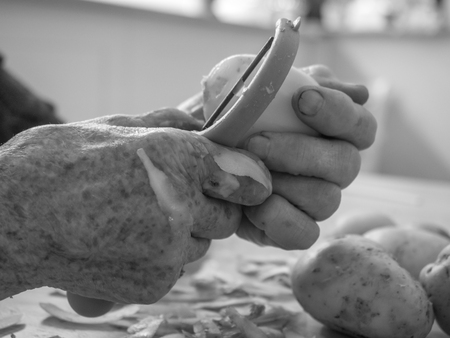 Old, hands are peeling potatoesの写真素材